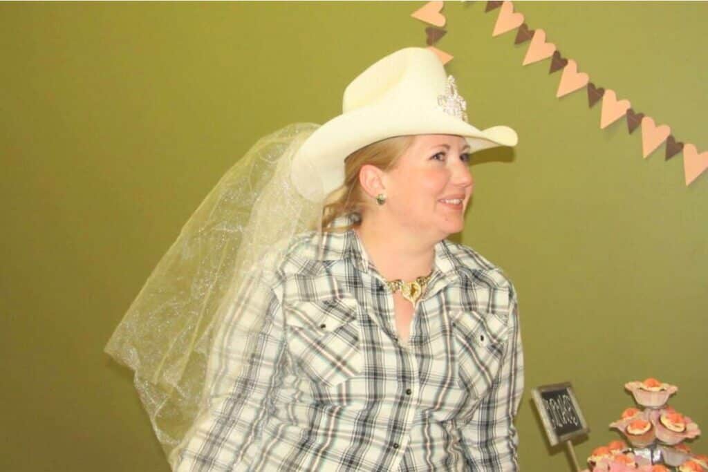 The bride to be, wearing a cowgirl hat with a tiara and a veil attached, at her cowgirl bridal shower.