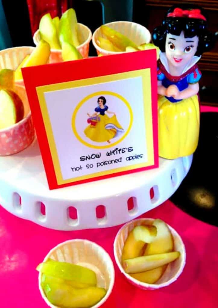 Sliced apples in pink snack cups and the food label says, "Snow White's Not So Poisoned Apples." A great choice for this princess birthday party.