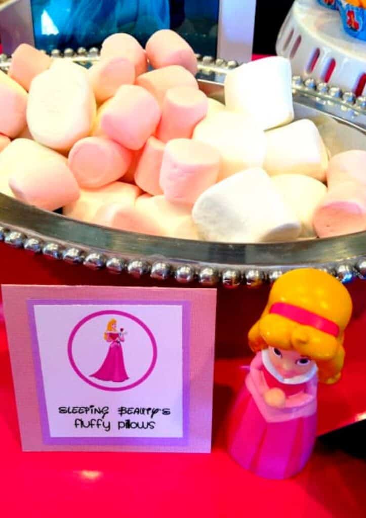 A large bowl of marshmallows with a food label that says, "Sleeping Beauty's pillows" for a princess birthday party.