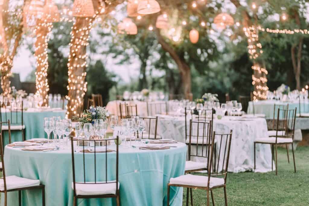 Elegant outdoor dinner setup with string lights and floral centerpieces for celebratory events.