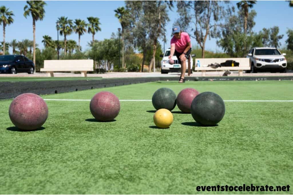 Bocce ball being played on grassy lawn.