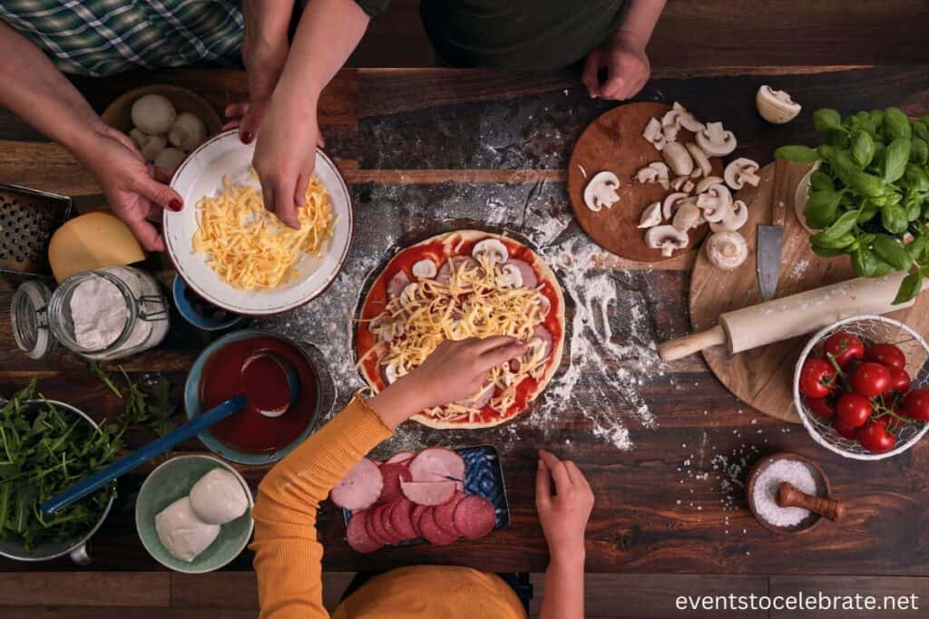 Kids or teens actively making their own pizzas at a hands-on cooking party, with toppings like cheese, pepperoni, and vegetables spread out on the table. The young chefs are having fun creating personalized pizzas, adding their favorite ingredients to the dough.