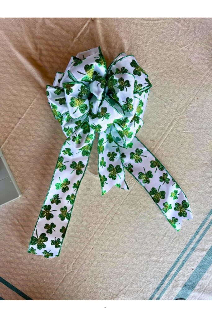 finished beautiful bow made with white ribbon with green and gold shamrocks all over it