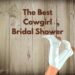 A white washed wood slat background with a pair of legs sticking up with cowboy boots on. The text overlay says, "The Best Cowgirl Bridal Shower"